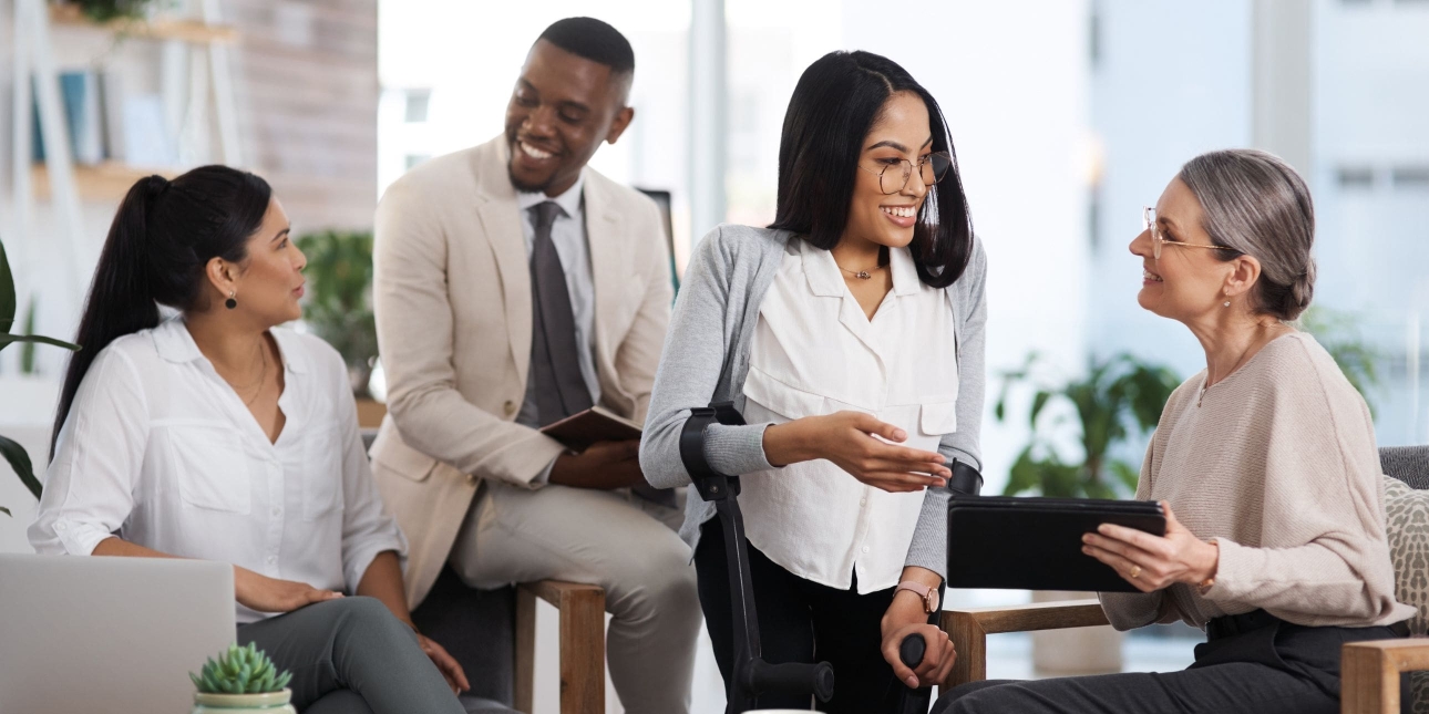 Four business colleagues - one man and three women – of different ages and ethnicities chatting in a casual office environment